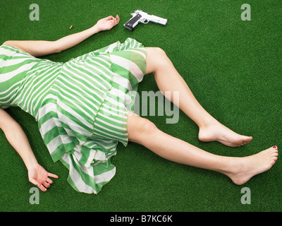 Woman lying on floor with gun Banque D'Images