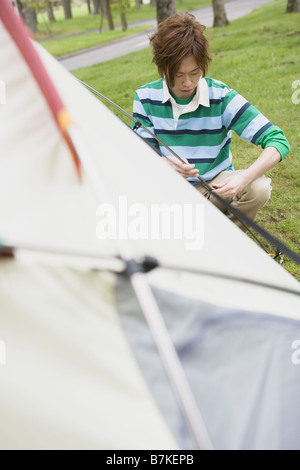 Jeune homme Ptching une tente Banque D'Images