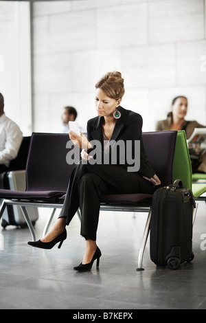 Woman holding cellulaire, l'attente Banque D'Images