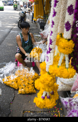 Fleurs d'oeillet de tri homme sur un étal au marché aux fleurs de Pak Khlong Talad Bangkok Thaïlande Banque D'Images