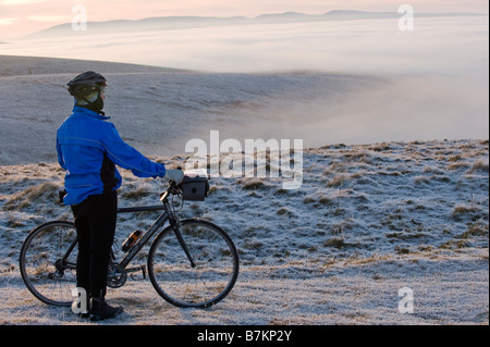 Cycliste admiring view de Tailbrigg au dessus de la vallée de l'Eden qui est couverte dans le brouillard avec des montagnes au loin au-dessus de la nuée Banque D'Images