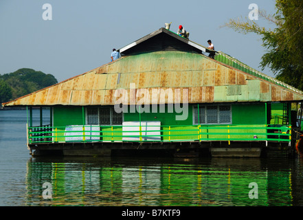 Les travailleurs sur le toit d'une maison colorée sur la rivière Kwai à Kanchanaburi Thaïlande Banque D'Images