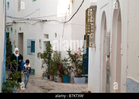 Femme et enfant marche dans une ruelle étroite, Asilah, Maroc Banque D'Images