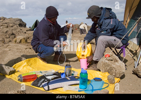 Porteurs d'eau de remplissage des bouteilles sur Shira camp Kilimanjaro en Tanzanie Banque D'Images