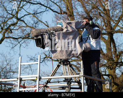 Caméraman de télévision à l'aide d'un événement sportif mauvais temps couvrir plus de son équipement Banque D'Images