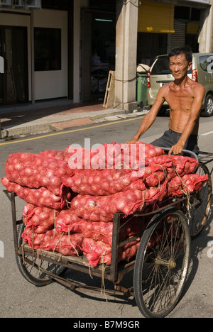 Homme transportant des sacs d'oignons sur un trishaw à Georgetown, Penang, Malaisie Banque D'Images