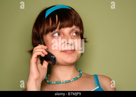 Jeune femme appelant par téléphone cellulaire sur green Banque D'Images