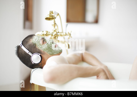 L'homme avec masque facial à écouter de la musique dans une baignoire Banque D'Images