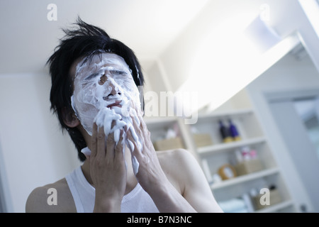 L'homme lave son visage dans une salle de bains Banque D'Images