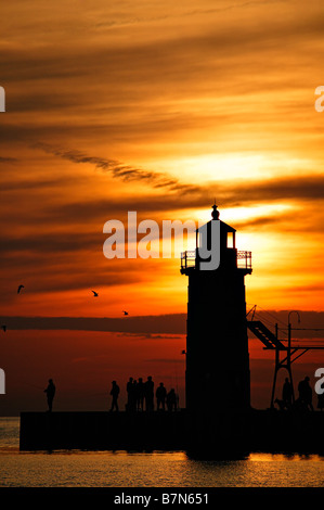 Un magnifique coucher de soleil met en évidence les gens se sont réunis sur la jetée sud ci-dessous phare de South Haven Banque D'Images