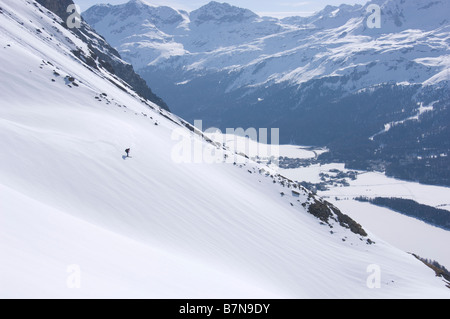 L'alpiniste Ski descend une pente en direction du lac gelé Sils et lac de Silvaplana. Grisons, Suisse Banque D'Images