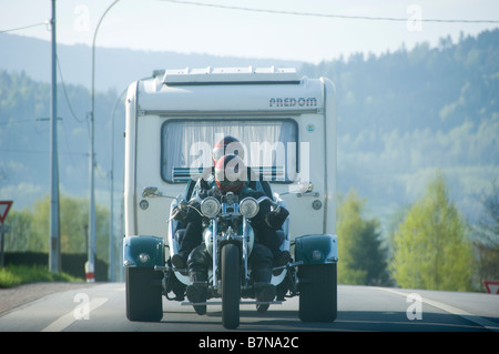 Couple riding a trike et la traction d'une caravane. Banque D'Images