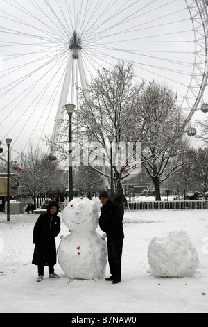 Bonhomme de neige en face de la grande roue de Londres avec tourisits debout sur les deux côtés Banque D'Images