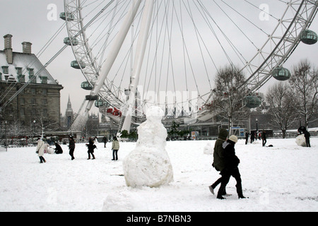 Les enfants jouent dans la neige en face de l'oeil de Londres tout en faisant un bonhomme de neige Banque D'Images