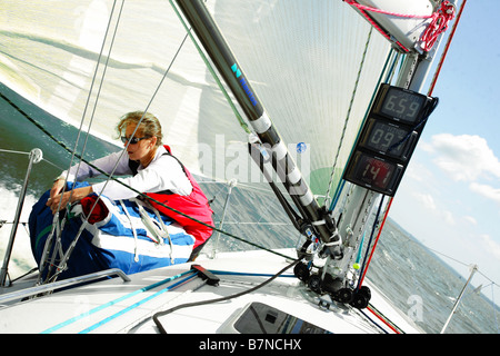 Marin femmes ranger une voile sur un yacht dans le Solent, au Royaume-Uni. Banque D'Images