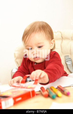 Dessin de l'enfant. Assis dans un fauteuil pour les enfants à la table. Banque D'Images