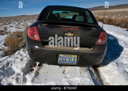 Une location de voiture Chevrolet noir est prisonnier sur une route enneigée à côté de l'armoise près de Summit Lake Nevada États-Unis d'Amérique Banque D'Images