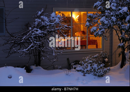 À la fenêtre d'accueil chaleureux en snowy night lights glowing à partir de la fenêtre . Banque D'Images