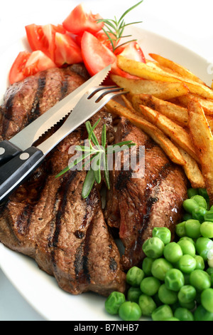 Un grill steak traditionnel avec pavé de rumsteak french fried chips de pomme de terre et les pois tomate garnie avec une branche de romarin Banque D'Images