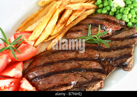 Un grill steak traditionnel avec pavé de rumsteak french fried chips de pomme de terre et les pois tomate garnie avec une branche de romarin Banque D'Images