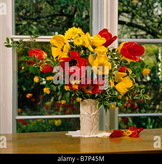 Tulipes rouges et jaunes dans un vase en verre blanc Banque D'Images