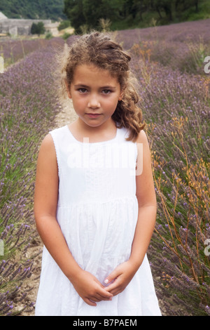 Beau 8 ans, fille, debout dans un champ de lavande avec l'abbaye de Sénanque en arrière-plan, Gordes, Vaucluse, France Banque D'Images