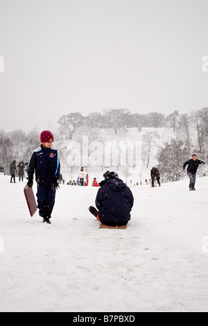 Les gens de la luge dans la neige couverts de Greenwich Park, Londres Banque D'Images