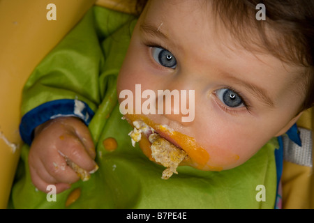 Une fille de bébé nourrir elle-même . Banque D'Images