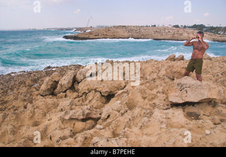 Man taking photo de grandes vagues se brisant sur des rochers dans les hauts vents près de Ayia Napa sur l'Est de l'île Méditerranéenne de Chypre UE Banque D'Images