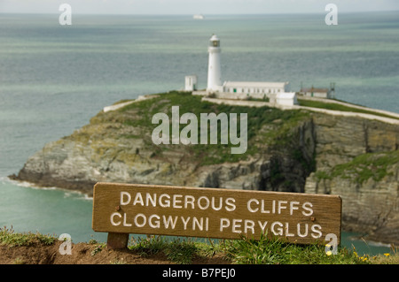 South Stack Island et phare avec un dangereux panneau Cliffs écrit en gallois et en anglais au premier plan. Île Anglesey. ROYAUME-UNI Banque D'Images