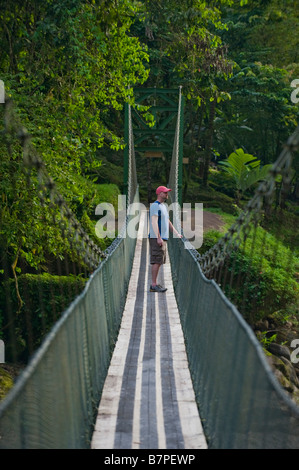 L'Amérique centrale, le Costa Rica. Un randonneur sur un pont suspendu sur la rivière Pacuare sauvage et magnifique. Banque D'Images