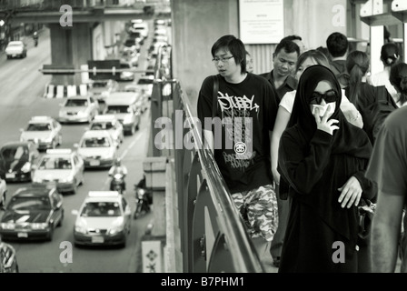 Femme essayant d'éviter la pollution du trafic avec un mouchoir Pathumwan, dans le centre de Bangkok, Thaïlande Banque D'Images