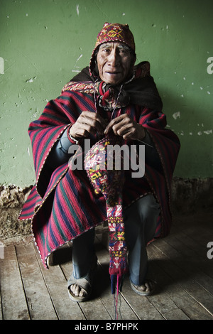 Un homme âgé, à la suite de la tradition andine, tisse lui-même un nouveau chapeau de laine d'alpaga. Banque D'Images