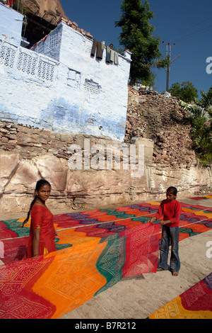 Indian woman and boy avec des textiles séchant au soleil dans les rues de jodhpur avec brahmane peint bleu traditionnel Banque D'Images