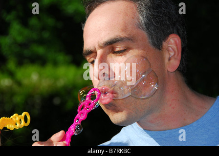 Homme soufflant des bulles de savon Banque D'Images