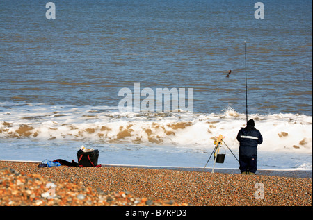 Pêcheur à la ligne en mer de rembobinage sur plage de Salthouse, Norfolk, Royaume-Uni. Banque D'Images