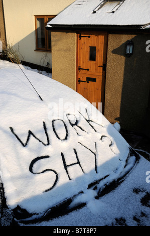 Voiture garée sur une allée AVEC DES MOTS ÉCRITS DANS LA NEIGE TIMIDE TRAVAIL suggérant l'ABSENTÉISME AU TRAVAIL PENDANT LES CONDITIONS HIVERNALES modérées Banque D'Images