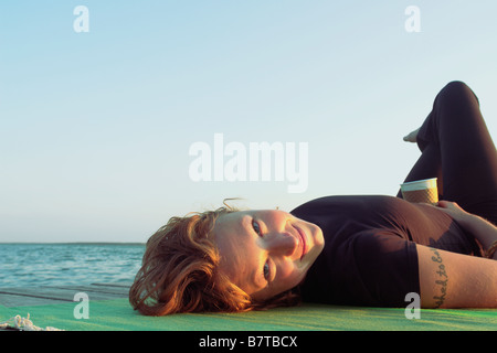 Woman lying on dock en lac, Clear Lake, parc national du Mont-Riding, Manitoba, Canada Banque D'Images