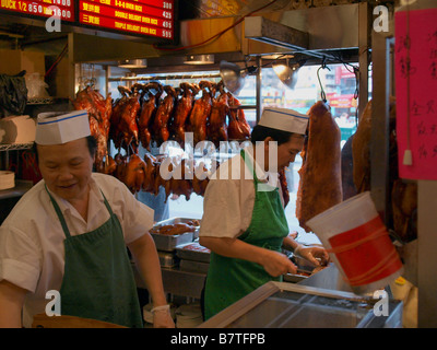 Chefs chinois dans un restaurant chinois dans le quartier chinois de Manhattan entouré de canard rôti, pick, poulet et autres viandes. Banque D'Images