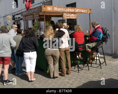 Les gens foule autour d'un étal vendant les saucisses allemandes au marché du dimanche de Teguise Lanzarote la plus grande dans les îles Canaries Banque D'Images