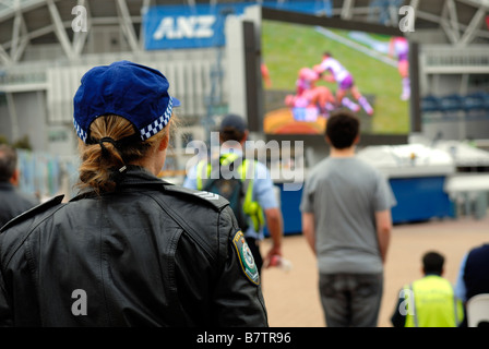 Sydney femme Police Woman watching 2008 NSW Rubgy League Grand final sur l'écran de l'extérieur, le Parc Olympique, Sydney, Australie Banque D'Images