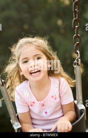 Little girl playing on swing laughing