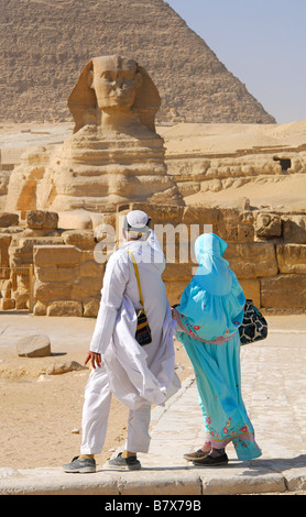 Le Caire, Égypte. Un couple en tenue traditionnelle, regardant le Sphinx de Gizeh, avec la Grande Pyramide derrière. L'année 2009. Banque D'Images