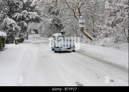 Voiture roulant sur une route de campagne enneigée Banque D'Images
