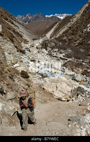 Porter népalais transportant des marchandises à Dingboche environs en parc national de Sagarmatha Vallée de l'Everest région de Khumbu au Népal Banque D'Images