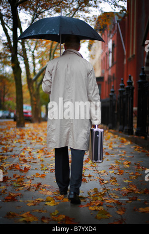 Homme marchant dans la rue sous un parasol Banque D'Images