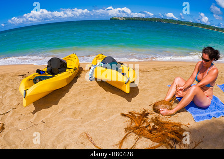 Femme de l'ouverture d'une noix de coco sur la plage à la baie de Hanalei île de Kauai Hawaii Banque D'Images