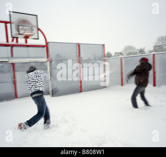 Photo d'action de deux adolescents ayant une bataille de boules de neige dans une tempête de neige avec mouvement délibéré et flou. Banque D'Images