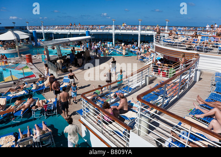 Les passagers des navires de croisière se prélasser sur la terrasse autour de la piscine sur Royal Caribbean Navigator of the Seas Banque D'Images