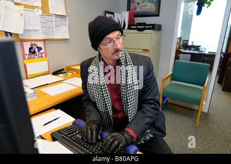 Hacker mâle regardant par-dessus son épaule dans un bureau alors que l'intrusion dans le système informatique d'une organisation Banque D'Images